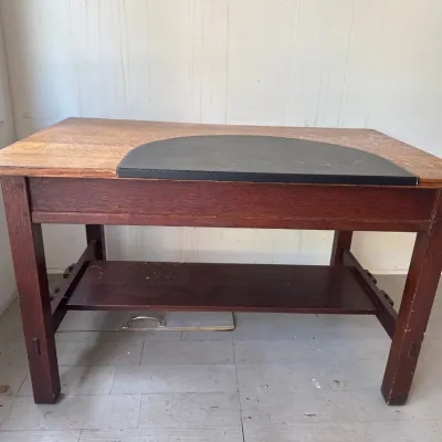 Vintage Mission-style oak library desk or workbench featuring a lower shelf and a black desk pad inset on top.