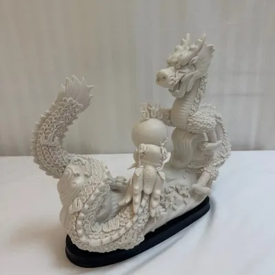 Sale Photo Thumbnail #56: Intricately carved white resin or faux-ivory dragon figurine on a black base, featuring detailed scales and a flaming pearl.