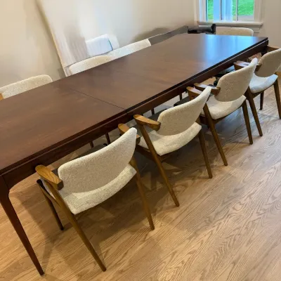 Sale Photo Thumbnail #28: Mid-century modern extension dining table in rich walnut stain, paired with matching upholstered armchairs featuring light tweed fabric.