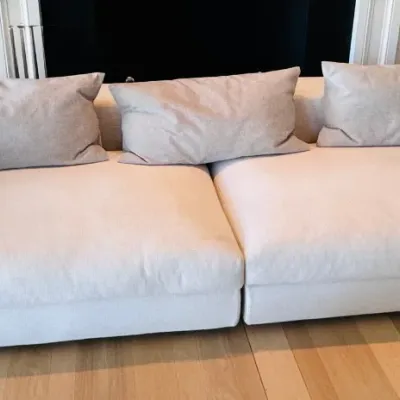 Sale Photo Thumbnail #6: Modern minimalist low-profile sectional sofa upholstered in light cream fabric with broad track arms and three matching lumbar pillows.