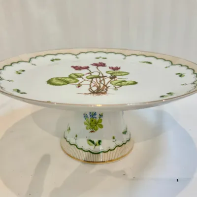 Sale Photo Thumbnail #40: Portmeirion 'The Botanic Garden' porcelain pedestal cake stand, featuring cyclamen and forget-me-not botanical illustrations with gold-tone trim.