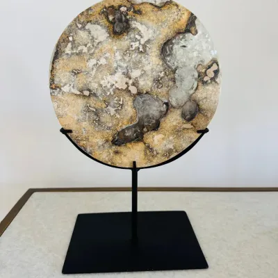 Sale Photo Thumbnail #18: Circular polished stone disc sculpture, featuring swirling neutral earth tones and quartz inclusions, presented on a black metal display stand.