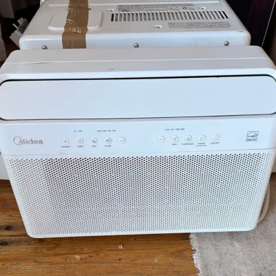 Sale Photo Thumbnail #58: Modern white Midea U-shaped window air conditioner featuring smart controls, Energy Star rating, and digital display.