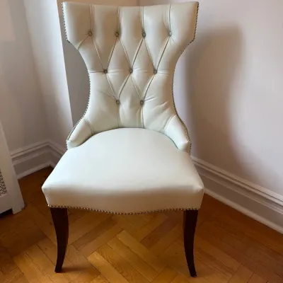 Sale Photo Thumbnail #38: Off-white leather or vinyl accent chair featuring a button-tufted hourglass back, silver nailhead trim, and dark wood legs.