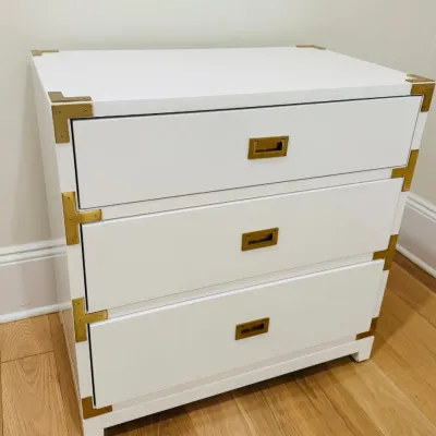 Sale Photo Thumbnail #4: White campaign-style three-drawer chest featuring brass recessed hardware and corner brackets.
