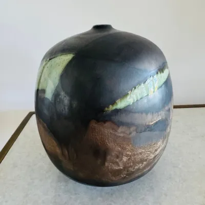Sale Photo Thumbnail #14: Studio pottery vessel with an organic rounded form, featuring an abstract metallic dark glaze with muted green and earth-tone accents.