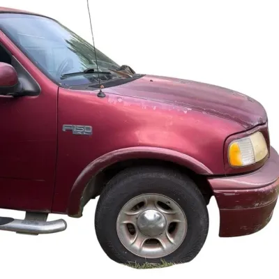 Front quarter view of a late-1990s to early-2000s maroon Ford F-150 XL pickup truck showing clearcoat peeling on the hood and fender.