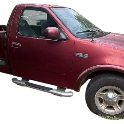 Late 1990s to early 2000s Ford F-150 XL regular cab pickup truck in maroon with side steps and visible exterior paint wear.