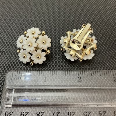 Sale Photo Thumbnail #42: Pair of vintage floral clip-on earrings featuring white molded plastic/lucite flower petals cluster-set around gold-tone center beads and frame. Each earring measures approximately 1 inch in diameter. In good condition with light wear consistent with age;