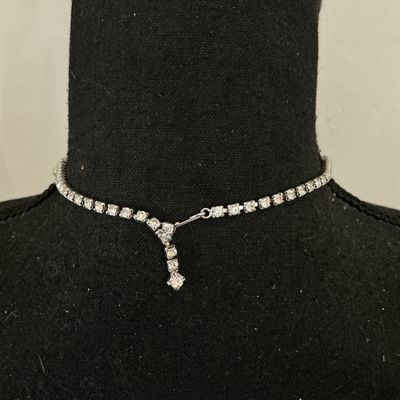 Sale Photo Thumbnail #244: A vintage clear rhinestone choker-style necklace featuring a scalloped drape front design set with round and baguette-cut stones in a silver-tone metal setting. Includes an adjustable hook closure chain. Appears to be in good vintage condition with all st