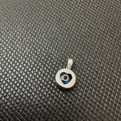 Sale Photo Thumbnail #5: A small sterling silver pendant featuring a central blue glass heart-shaped evil eye (nazar) detail surrounded by a Greek key border motif. The bail is stamped '925' indicating sterling silver content. Measures approximately 1/2 inch in diameter (excludin