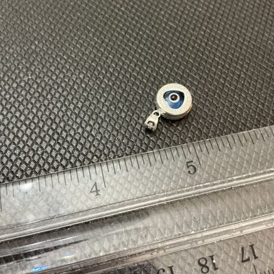Sale Photo Thumbnail #6: A small sterling silver pendant featuring a central blue glass heart-shaped evil eye (nazar) detail surrounded by a Greek key border motif. The bail is stamped '925' indicating sterling silver content. Measures approximately 1/2 inch in diameter (excludin