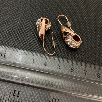 Sale Photo Thumbnail #195: Pair of rose gold-tone drop wire earrings featuring curved leaf-like wraps set with pave rhinestones/crystals. Includes plastic safety backings. Overall length measures approximately 2.5 cm (1 inch) as shown against ruler. Good pre-owned condition with al