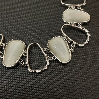 Sale Photo Thumbnail #52: Silver-tone metal statement bracelet featuring open geometric links accented with clear rhinestones and alternating faux cat's eye / opalescent stones. Features a lobster claw clasp with an adjustable extender chain. Measures approximately 7 to 8 inches i