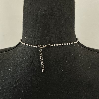 Sale Photo Thumbnail #234: Silver-tone collar necklace featuring set clear sparkly rhinestones in a cascading V-shape design along the front. Features a single strand of rhinestones along the back with a lobster claw clasp and adjustable extension chain. Appears to be in good pre-o