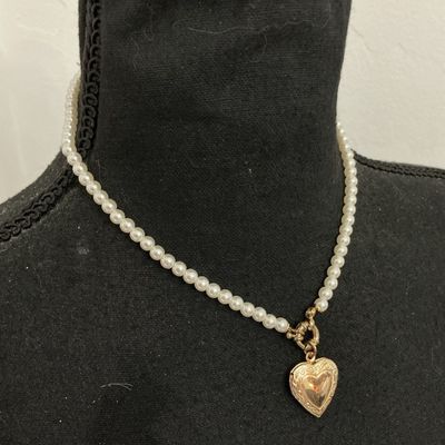 Sale Photo Thumbnail #212: Faux pearl strand necklace featuring a gold-tone, scroll-embossed heart locket attached by a front toggle clasp. The heart locket opens to hold a small photo. The back features a lobster claw clasp with an adjustable extender chain. Good overall condition