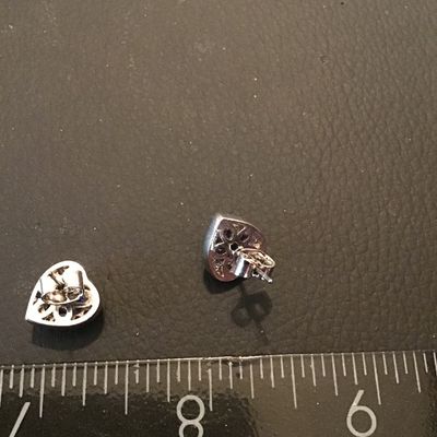 Sale Photo Thumbnail #216: Pair of silver-tone stud earrings featuring heart-cut purple central stones surrounded by halo borders of clear accent stones. Secured with post backs. Good overall condition.