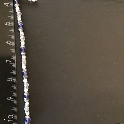 Sale Photo Thumbnail #74: A beaded costume bracelet featuring alternating faceted purple glass or crystal beads, faceted clear glass beads, small faux pearls, and textured metal spacer beads. It fastens with a silvertone rope-texture toggle clasp and includes a short decorative da
