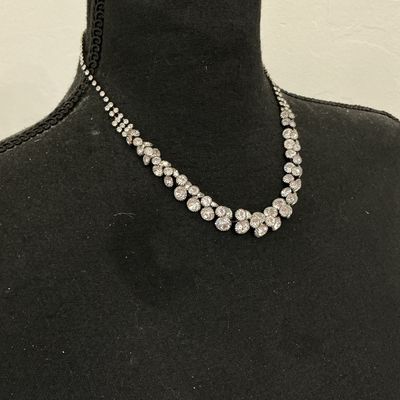 Sale Photo Thumbnail #231: Silver-tone collar necklace featuring set clear sparkly rhinestones in a cascading V-shape design along the front. Features a single strand of rhinestones along the back with a lobster claw clasp and adjustable extension chain. Appears to be in good pre-o