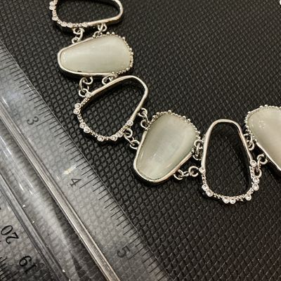 Sale Photo Thumbnail #54: Silver-tone metal statement bracelet featuring open geometric links accented with clear rhinestones and alternating faux cat's eye / opalescent stones. Features a lobster claw clasp with an adjustable extender chain. Measures approximately 7 to 8 inches i