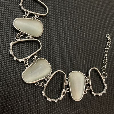 Sale Photo Thumbnail #50: Silver-tone metal statement bracelet featuring open geometric links accented with clear rhinestones and alternating faux cat's eye / opalescent stones. Features a lobster claw clasp with an adjustable extender chain. Measures approximately 7 to 8 inches i