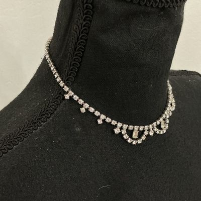 Sale Photo Thumbnail #243: A vintage clear rhinestone choker-style necklace featuring a scalloped drape front design set with round and baguette-cut stones in a silver-tone metal setting. Includes an adjustable hook closure chain. Appears to be in good vintage condition with all st