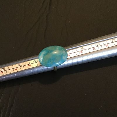 Sale Photo Thumbnail #143: Adjustable costume ring featuring a brass-tone band set with a large oval blue mottled stone or cabochon (turquoise-style appearance). Appears to be in good pre-owned condition with minor surface wear to the metal band.
