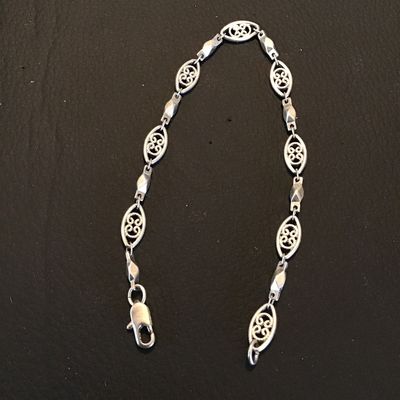 Sale Photo Thumbnail #246: Silver-tone link chain bracelet featuring delicate openwork filigree oval links interspersed with polished Bar links. Measures approximately 7 inches long with a lobster claw clasp. Good condition with light surface wear.