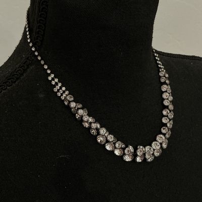 Sale Photo Thumbnail #230: Silver-tone collar necklace featuring set clear sparkly rhinestones in a cascading V-shape design along the front. Features a single strand of rhinestones along the back with a lobster claw clasp and adjustable extension chain. Appears to be in good pre-o