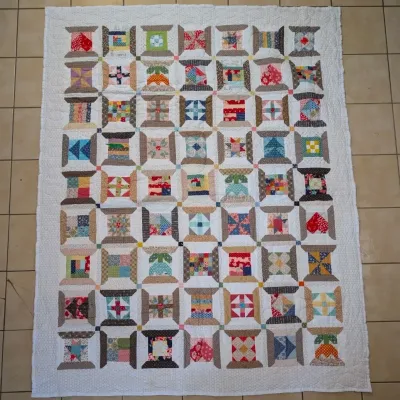 Sale Photo Thumbnail #17: Handmade spool pattern patch quilt featuring colorful mixed fabric blocks set against a quilted white border.