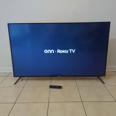 Sale Photo Thumbnail #57: onn. brand Roku smart flat-screen television with original remote control, shown powered on.