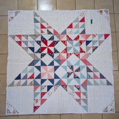 Sale Photo Thumbnail #19: Handmade patchwork star quilt featuring a central geometric star motif composed of colorful patterned triangles on a white background.