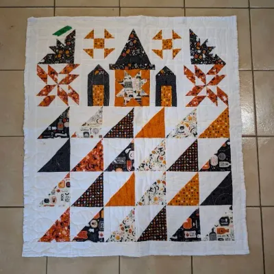 Sale Photo Thumbnail #39: Handmade Halloween-themed patchwork lap quilt featuring haunted house motifs, pinwheels, and half-square triangles in black, orange, and white fabrics.