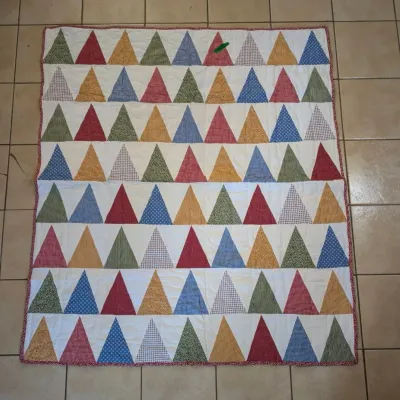 Sale Photo Thumbnail #47: Handmade patchwork quilt featuring rows of colorful geometric triangle trees against a white background with red piping.