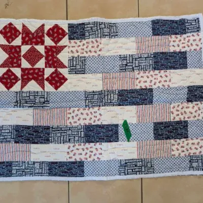 Sale Photo Thumbnail #42: Handcrafted patriotic flag-themed mini quilt featuring red, white, and blue Americana patterned fabrics and a star block canton.
