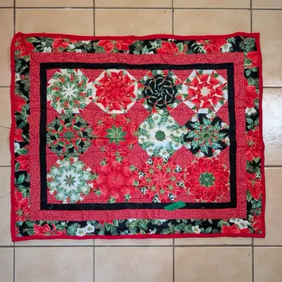 Sale Photo Thumbnail #43: Handmade Christmas-themed quilted wall hanging featuring kaleidoscope or starburst blocks with poinsettia and evergreen floral prints.