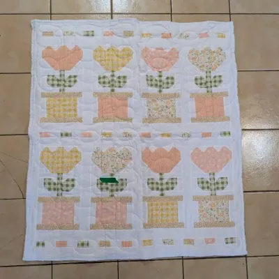 Sale Photo Thumbnail #20: Handmade patchwork quilt featuring pastel tulip and flowerpot motifs in yellow, pink, and floral fabrics set against a white background.