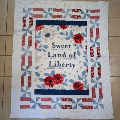 Sale Photo Thumbnail #37: Handcrafted patriotic patchwork quilt featuring a central panel reading 'Sweet Land of Liberty' surrounded by red, white, and blue pinwheel borders.