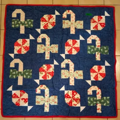 Sale Photo Thumbnail #45: Handmade Christmas throw quilt featuring candy cane and peppermint candy pieced blocks on a navy blue background with a red border.