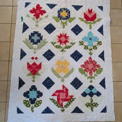 Sale Photo Thumbnail #27: Handmade quilt featuring colorful floral patchwork blocks on a white stitched background with blue diamond accents.