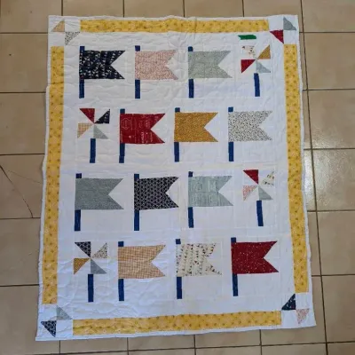 Sale Photo Thumbnail #41: Handmade patchwork quilt featuring nautical flag and pinwheel blocks framed by a yellow floral border.