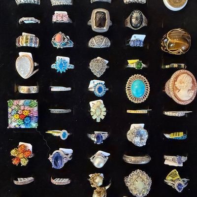 Collection of assorted statement and fashion rings displayed in a black velvet tray, featuring gemstone, cameo, pearl, and sterling...