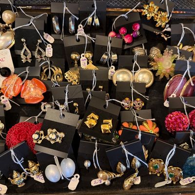 Large collection of vintage clip-on and pierced earrings displayed on black jewelry cards inside a velvet-lined case.