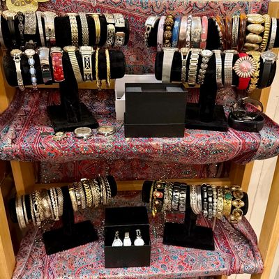 Large collection of vintage and modern women's watches, bangles, and bracelets displayed on black velvet T-bar stands over a...