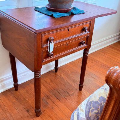 Sale Photo Thumbnail #55: Antique drop-leaf sewing stand featuring two small drawers with wooden knobs and turned legs, late 19th to early 20th century.