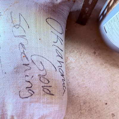 Sale Photo Thumbnail #97: Large woven plastic sandbag handwritten with "Oklahoma Gold Screening" in black marker.