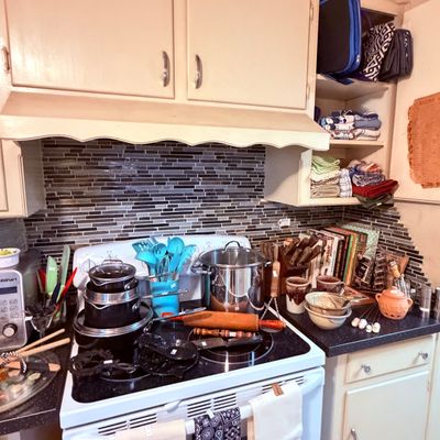 Sale Photo Thumbnail #62: Assorted kitchenware including pots, pans, teal cooking utensils, a rolling pin, cookbooks, and pottery mug sets