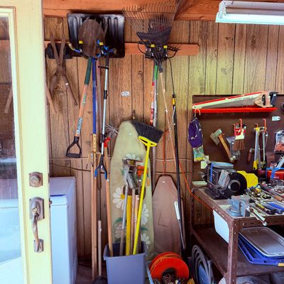 Sale Photo Thumbnail #94: Collection of assorted yard tools, long-handled equipment, and workshop items, including shovels, rakes, brooms, and bench grinders