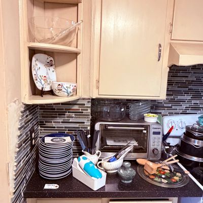 Sale Photo Thumbnail #61: Collection of kitchen items including a stainless steel Cuisinart toaster oven, blue rimmed dinnerware stack, handheld immersion blender, and various glass serving pieces.