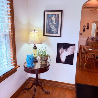 Sale Photo Thumbnail #18: Round mahogany accent table featuring a brass-accented lamp, turquoise ceramic owl figurine, and potted plant, paired with owl-themed wall art.